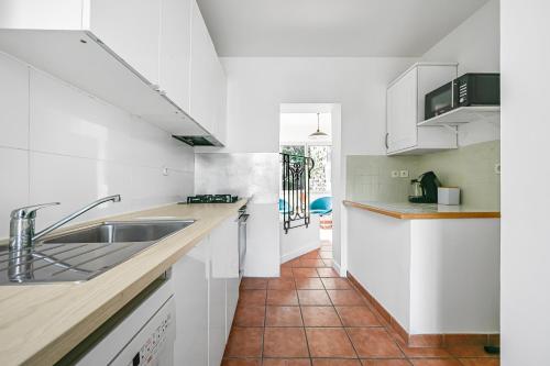 une cuisine avec des armoires blanches et un sol carrelé dans l'établissement La Meulière - Maison charmante proche de Paris, à Bagneux