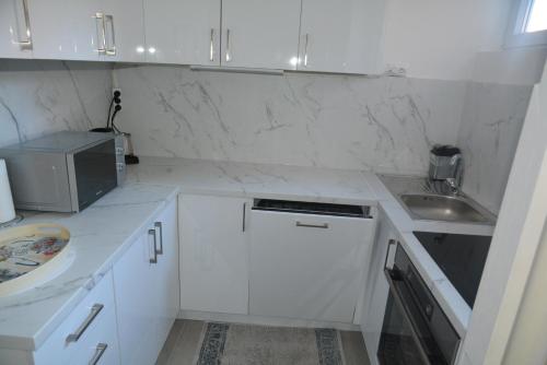 a white kitchen with white cabinets and a sink at Turquoise Apartment in Novi Pazar
