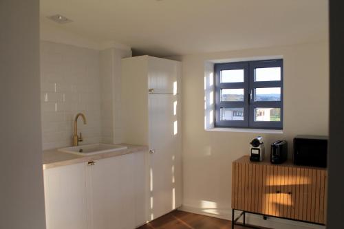 a white kitchen with a sink and a window at Hotel Apartamentos Casas da Fortaleza in Lugo