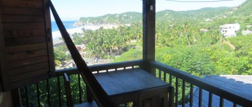 a balcony with a bench looking out at the beach at LA LOMA LINDA, Bungalows, Yoga and Feldenkrais, STARLINK INTERNET in Zipolite