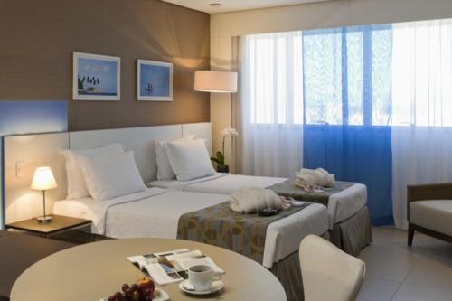 a hotel room with two beds and a table at Intercity Salvador in Salvador