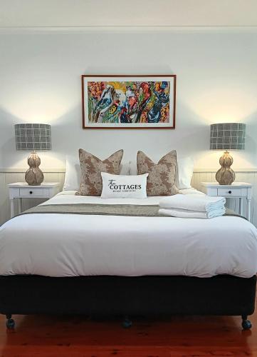 a bedroom with a large white bed with two lamps at The Cottages On Mount Tamborine in Mount Tamborine