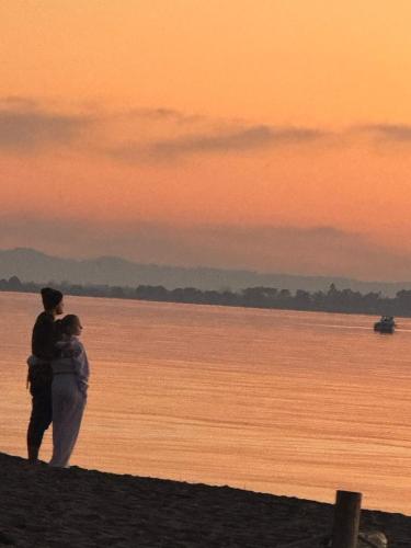 a man and woman standing on the beach at sunset at Deluxe Apartments Shengjin in Shëngjin