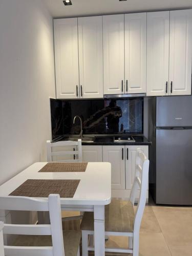 a kitchen with white cabinets and a white table and chairs at Deluxe Apartments Shengjin in Shëngjin