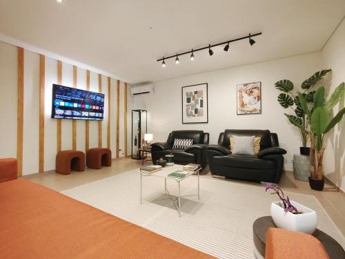 a living room with black furniture and a flat screen tv at Douro Valley View Apartments in Armamar