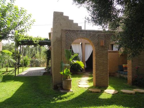 a brick house with an archway in a yard at DAR TITRIT Charming house with garden and pool in Akhatar