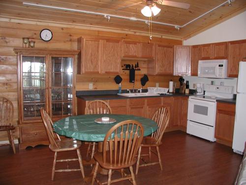 a kitchen with a table and chairs and a kitchen with wooden cabinets at Nantahala Cabins in Bryson City