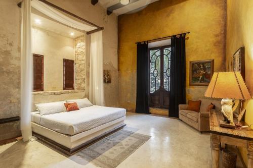 a bedroom with a bed and a couch and a window at Hacienda Sacnicte in Izamal