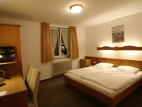 a bedroom with a bed and a desk and a television at Hotel Gasthof Bären in Weingarten