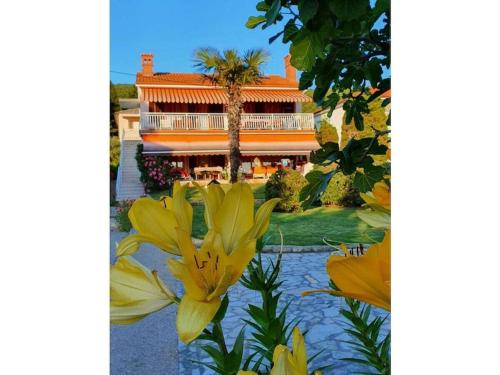 a building with a palm tree and yellow flowers at Holiday apartment in Punat with swimming pool in Punat