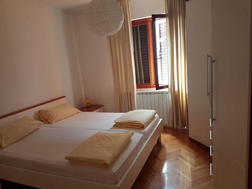 a bedroom with a bed with white sheets and a window at Holiday apartment in Punat with swimming pool in Punat