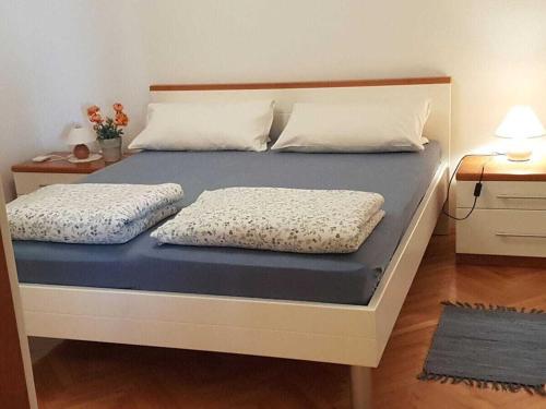 a bed with two pillows on top of it at Holiday apartment in Punat with swimming pool in Punat