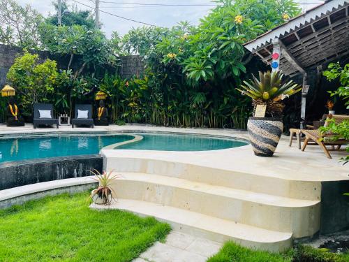 a swimming pool with stairs next to a yard at Villa Bali Santai in Kerobokan