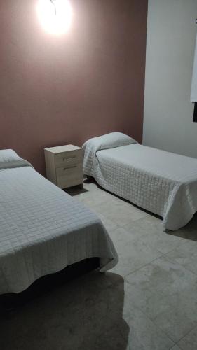 una camera con due letti e un comodino di Mis Dos corazones a Villa Gesell