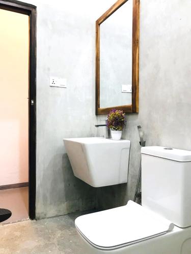 a bathroom with a sink and a toilet and a mirror at Seaware Flowers in Arugam Bay
