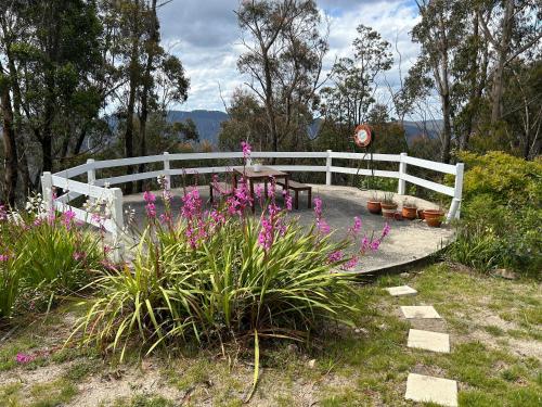 a white fence with a table and some flowers at Mountain Tranquility in Mount Tomah