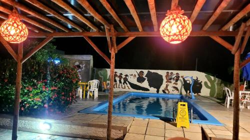 ein Pool in einem Pavillon mit Lichtern und einem Wandgemälde von Kühen in der Unterkunft Pousada Porto dos Corais in Maragogi