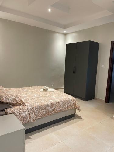 达喀尔Logement standing moderne au centre de Dakar的一间卧室配有一张床和一个黑色橱柜