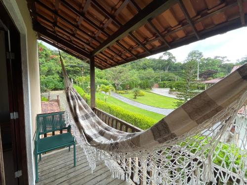 a hammock on a porch with a green chair at Pousada Monteflor Guaramiranga-CE in Guaramiranga