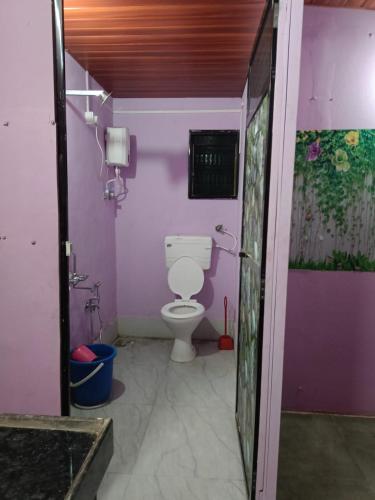 a bathroom with a toilet and a clock on the wall at Shree Swa Cottage Revdanda in Alībāg