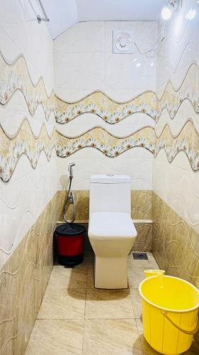 a bathroom with a toilet and a yellow bucket at mountain lake view private pool villa -Wayanad in Meppādi