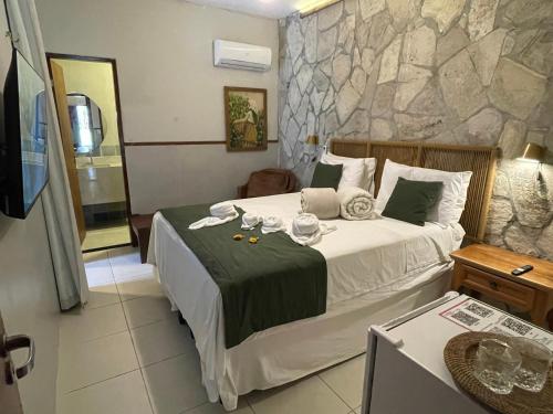 a bedroom with a large bed with a stone wall at Pousada Monteflor Guaramiranga-CE in Guaramiranga