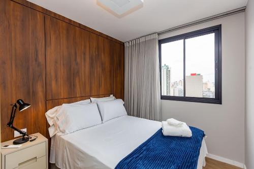 a bedroom with a white bed and a window at Apto confortável Centro/Batel in Curitiba