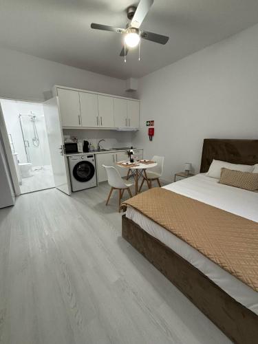 a bedroom with a bed and a table and a kitchen at Casa da Praça I in Vila Nova