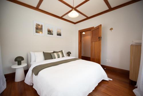 a bedroom with a white bed and a wooden ceiling at Pohutukawa Tides - Walk to Beach, Large Fenced Section in New Plymouth