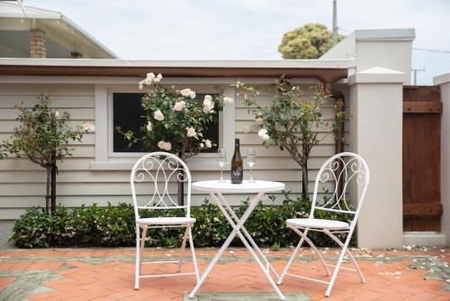 two chairs and a table with a bottle of wine at Pohutukawa Tides - Walk to Beach, Large Fenced Section in New Plymouth