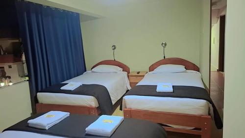 two beds in a room with blue curtains at Kuntur House Machupicchu in Machu Picchu