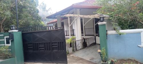 a house with a black gate and a blue fence at Johans Villa Kandy in Kandy