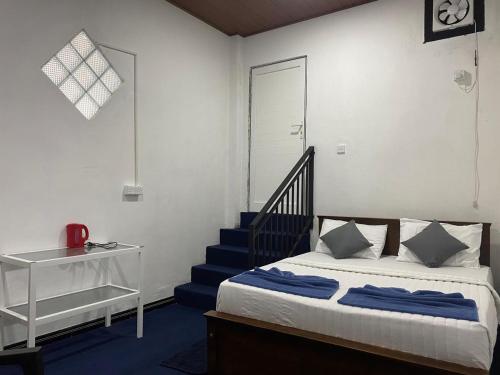 a bedroom with a bed with blue sheets and a staircase at YaYa Lodge Haputale in Haputale