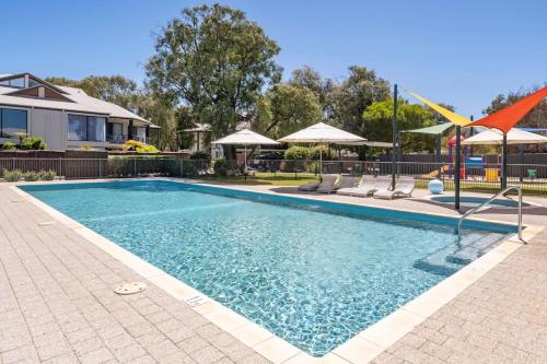 a swimming pool with chairs and umbrellas at 20CapeView Geographe bay in Busselton
