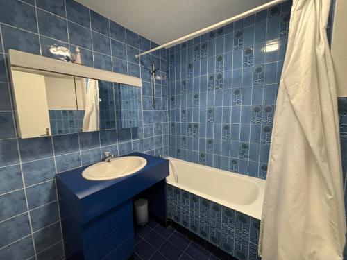 une salle de bain carrelée bleue avec un lavabo et une baignoire dans l'établissement Studio spacieux avec balcon, vue mer, Les Sables d'Olonne - FR-1-197-618, à Les Sables-dʼOlonne