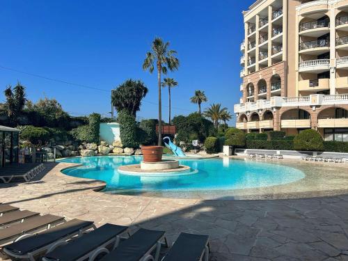 une piscine avec des chaises longues et un bâtiment dans l'établissement Cannes la Bocca: Appartement 2 Pièces avec Terrasse et Piscines - FR-1-609-110, à Cannes
