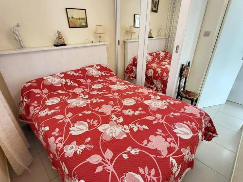 - une chambre dotée d'un couvre-lit rouge et de fleurs dans l'établissement T2 confortable avec jardin, Wi-Fi et parking à 400m des plages - FR-1-316-345, à Six-Fours-les-Plages