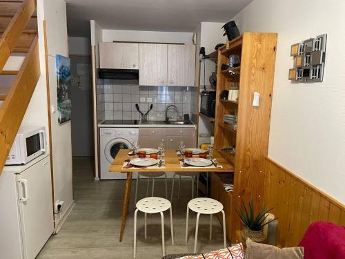 - une petite cuisine avec une table et deux tabourets dans l'établissement Duplex 39m², central à Cauterets, proche toutes commodités - FR-1-812-132, à Cauterets
