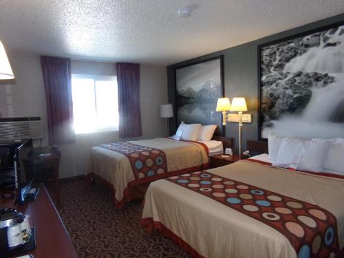 a hotel room with two beds and a television at Super 8 by Wyndham Gillette in Gillette