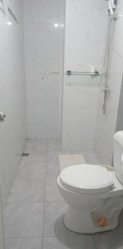 a white bathroom with a toilet and a shower at JYL Royal Oceancrest Mactan Condo Staycation in Mactan Island