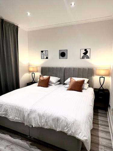 a bedroom with a large white bed with two lamps at Luxury home in prime location Steps from WoodGreen in London