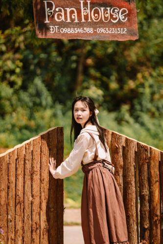 a young girl standing next to a wooden fence at Pan House Bắc Hà in Bắc Hà