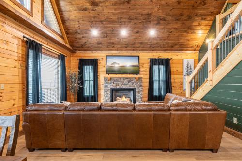 a brown leather couch in a room with a fireplace at Cozy Mountaintop Cabin with Firepit, HotTub & Views! in Sevierville