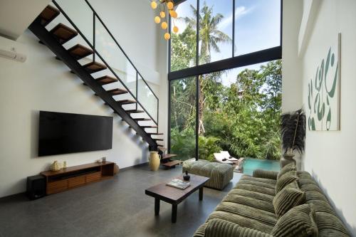 a living room with a large couch and a staircase at Unique Riverside Sanctuary 2BR Villa in Tumbak Bayuh