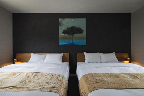 a bedroom with two beds and a tree on the wall at THE HERO VILLA 米原ビーチリゾートishigaki in Ishigaki Island