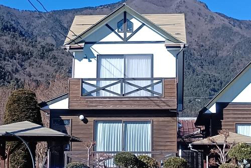 a house with a mountain in the background at 貸別荘Lealeaプライベートコテージ in Fujikawaguchiko