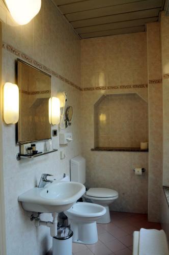 une salle de bain avec un lavabo, des toilettes et un miroir dans l'établissement Hotel Button, à Parme