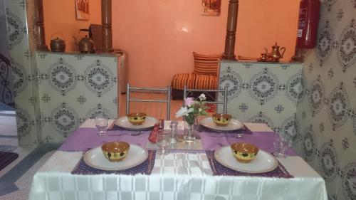 a table with plates and glasses on top of it at Elmenzah Apartments in Taroudant