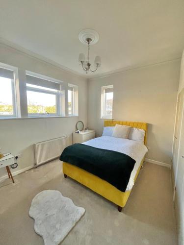 a bedroom with a bed and two windows at The Bunker, Golf Cottage in Prestwick