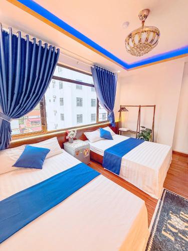 カットバ島にあるVENUS HOTEL catbaの青いカーテンが備わる客室のベッド2台